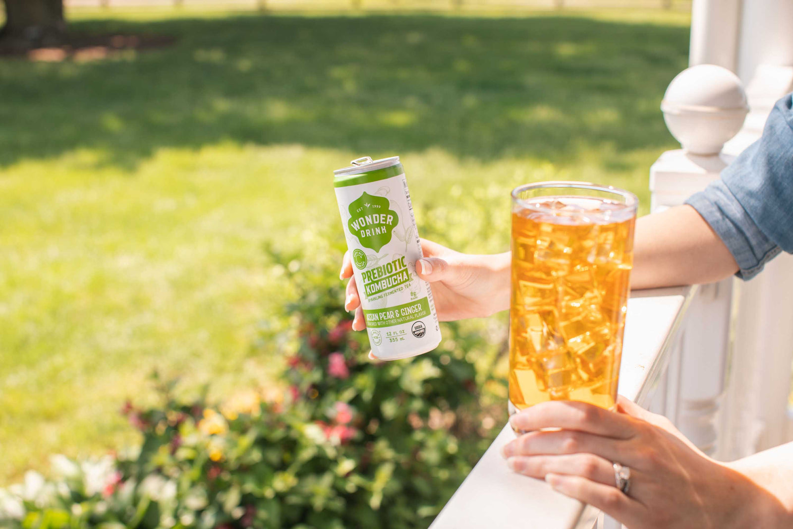 Standing outside holding a can and glass of wonder drink Kombucha