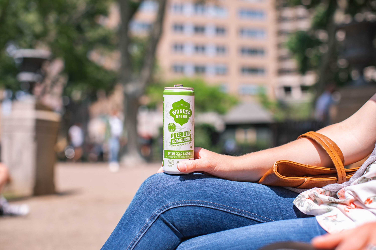 Someone sitting in the park with can of Kombucha